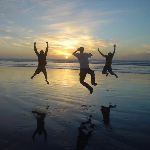 three people jumping on the beach